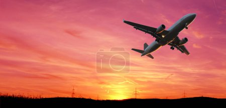 Téléchargez les photos : Silhouette noire d'avion dans un beau ciel dramatique coloré avec nuage, beau coucher de soleil, vol concept dans l'espace céleste, calme méditatif et grandeur, transport, transport de marchandises - en image libre de droit