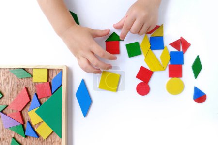 Kinderhände schaffen Bilder aus farbigen geometrischen Holzformen, kleines Kind, Mädchen 3 Jahre alt, das mit Lernspielzeug spielt, Konzeptkindern Fantasie, einzigartige Kunstwerke, fertige Kunstwerke