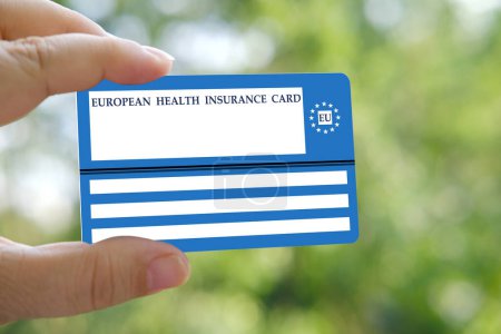 Photo for European insurance healthcare card in female hand on natural green background, EU document healthcare support, medical expenses, emergency, healthcare safety, international healthcare assistance - Royalty Free Image