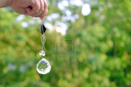 Téléchargez les photos : Mains féminines avec boule de verre cristal gros plan sur fond naturel vert, balançoires pendule, harmonie avec la nature, énergie spirituelle et équilibre, divination et voyance, magie et éveil - en image libre de droit