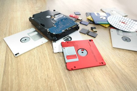 Foto de Dispositivos de almacenamiento de datos electrónicos retro vintage de los años 80, 90, disco cd, unidades flash, disco duro moderno dispersos en la mesa. Pila de disquetes en gris, negro, azul, amarillo, rojo, blanco - Imagen libre de derechos