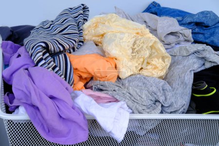 Photo for Colorful clothes randomly lying around in mesh basket, mess, chaos in dressing room, concept minimalism in clothing choices, promoting simplified and intentional wardrobe - Royalty Free Image