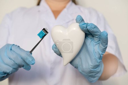Photo for Female scientist, doctor holding heart model, microprocessor, microchip, biochip tweezers for immunocytochemical studies heart, treatment cardiovascular disease, experimental nanotechnology medicine - Royalty Free Image