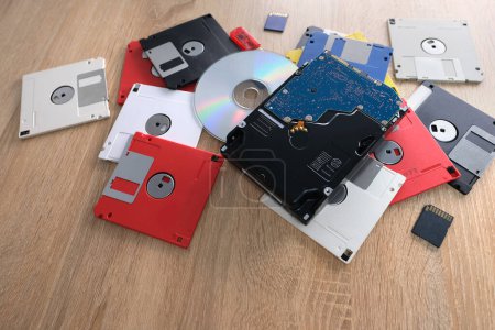 Foto de Dispositivos de almacenamiento de datos electrónicos retro vintage de los años 80, 90, disco cd, unidades flash, disco duro moderno dispersos en la mesa. Pila de disquetes en gris, negro, azul, amarillo, rojo, blanco - Imagen libre de derechos