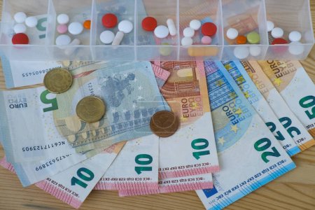 20, 50-Euro-Banknoten, Münzen, Pillen, Kapseln, Vitamine im Pillenregal, teure Medikamente für Kranke, finanzielle Unterstützung für Patienten, Sicherstellung der Medikamenteneinhaltung, Gesundheitsförderung