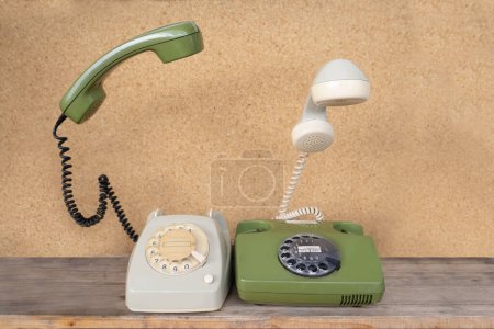 Photo for Two classic phones with levitating handsets with Disc Dial, phone handset levitates, flies in air, Secure Communication, Obsolete Technology, Retro Aesthetic 80s - Royalty Free Image