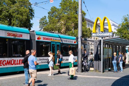 Foto de Parada de tranvía South Station, personas esperando la ruta de transporte deseada, McDonald 's sign over stop, sistema de transporte público alemán, infraestructura de transporte, Frankfurt - 10 de agosto de 2023 - Imagen libre de derechos