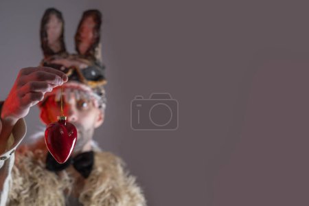 Photo for Cringe hare man, young guy in cringe in scary rabbit mask looks at heart, concept murderous love, Valentine's Day, fear and horror, facial expression, Love Strategies, Halloween and Festive Costumes - Royalty Free Image