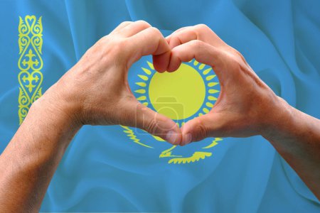 Téléchargez les photos : Gros plan des mains masculines en forme de cœur sur fond de drapeau national en soie du Kazakhstan, patriotes du concept de pays, fête de l'indépendance, voyage, coopération internationale - en image libre de droit