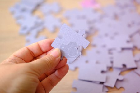 Téléchargez les photos : Pièce de puzzle en carton à la main féminine, assemblage de puzzle concept sur le bien-être psychologique, la relaxation et l'amélioration de l'humeur - en image libre de droit