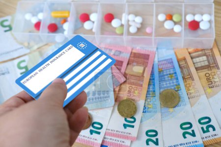 Photo for Healthcare cardholder holds European health insurance card, euros money, medicines, blue EU document healthcare support, medicines, medical expenses, emergency, healthcare guarantee - Royalty Free Image