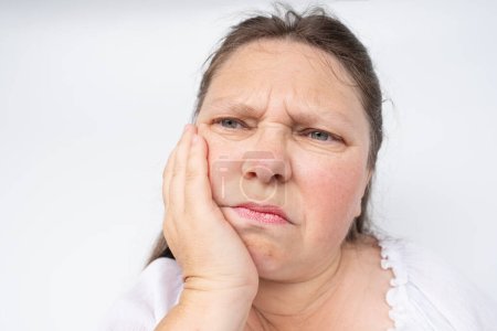 dolor dental insoportable, mujer madura de 50-55 años se aferra a la mandíbula, primer plano de la cara femenina con dolor de expresión facial, dolor dental insoportable, inflamación de los nervios dentales