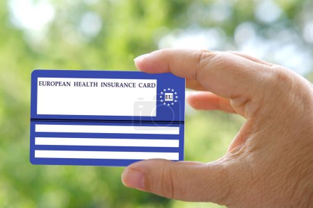 Carte européenne d'assurance maladie en main sur fond vert naturel, document bleu de l'UE soutien aux soins de santé, frais médicaux, urgence, assurance voyage UE et AELE voyage, informations sur les soins de santé