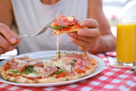 man eats Italian pizza, with salami, cheese, arugula, , male hands take pieces of pizza with salami, cheese, arugula, hands with food close-up, concept food tourism, culinary tradition, fast food