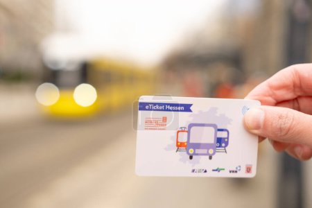 Photo for Male hand hold electronic Deutschland-Ticket, yellow tram Flexity Berlin driving down city street in Berlin, monthly travel pass in germany for public transport, Berlin, Germany - February 19, 2024 - Royalty Free Image