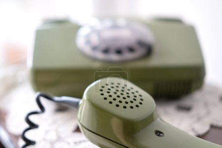 Foto de Auricular de teléfono verde, teléfono giratorio con esfera de disco, antigüedades bien mantenidas, tecnología obsoleta, estética retro 80 - Imagen libre de derechos