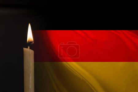 mourning candle burning front of flag Germany, Victims of cataclysm or war concept, memory of heroes served country, grief over loss, national unity in challenging times, state's history