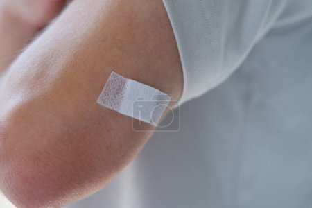 jeune homme après injection, gros plan sur l'avant-bras, plâtre blanc à portée de main, vaccin médical contre le virus COVID-19, vaccin contre la grippe saisonnière, vaccination pour les voyages