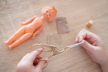 little girl's hands holding needle and fabric, showing focus while learning to sew clothes for doll, fine motor skills, sensory experience, preschool education