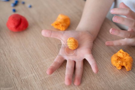 las manos de la niña rodando bolas coloridas playtough, arcilla colorida, determinación crea algo especial, habilidades motoras finas concepto, sensaciones táctiles, creatividad