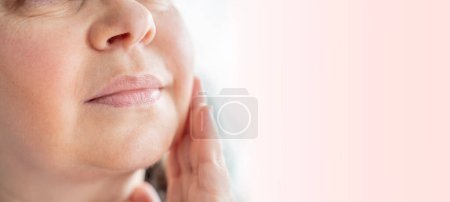 mature woman touches aging face, focusing on wrinkles, sagging and changes in facial contours, reflecting on natural process aging, Self-care practices, Skincare routine