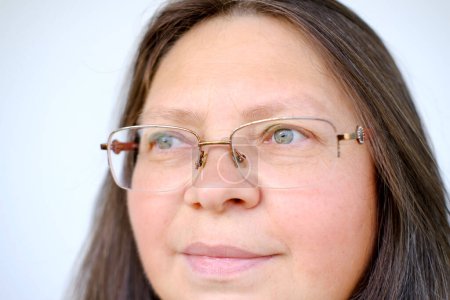 close-up female face of elderly woman 50 years old with long hair in glasses, on lips slight smile of maturity, emphasizing her wisdom, confidence, and natural beauty, Empowerment and Inspiration