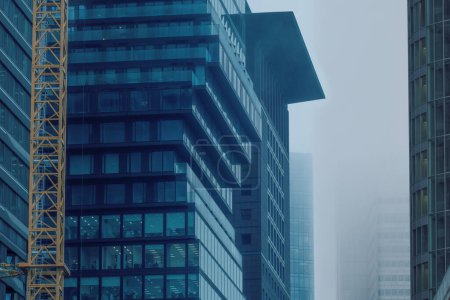 Téléchargez les photos : Gratte-ciel bâtiments disparaissent dans la brume, créant un paysage urbain mystérieux et atmosphérique avec des contours flous et des détails obscurcis, Conditions météorologiques, Ingénierie allemande - en image libre de droit