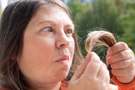 Examining role of hair inspection self-care routine and impact on self-image, mature woman examines Dry hair, brittle, split ends, Hair Health and Maintenance