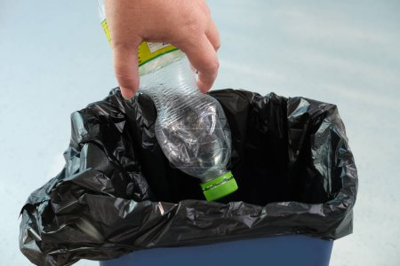 woman puts an empty plastic bottle in a recycling bin, close-up hands, the concept of household waste disposal, different types of garbage into different bins, waste recycling, reuse
