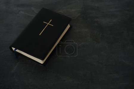 vieux livre noir, bible de famille en couverture sombre, croix d'or, plume d'oie, concept d'intermédiaire entre Dieu et le monde, valeurs chrétiennes éternelles, unité des hommes dans la foi
