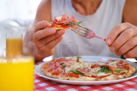 hombre come pizza italiana, con salami, queso, rúcula,, manos masculinas toman trozos de pizza con salami, queso, rúcula, manos con comida de cerca, concepto de turismo de alimentos, tradición culinaria, comida rápida