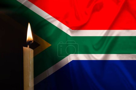 mourning candle burning front of flag South Africa, memory of heroes served country, grief over loss, national unity in challenging times, state's history