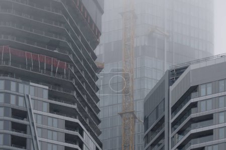 Téléchargez les photos : Gratte-ciel bâtiments disparaissent dans la brume, créant un paysage urbain mystérieux et atmosphérique avec des contours flous et des détails obscurcis, Conditions météorologiques, Ingénierie allemande - en image libre de droit