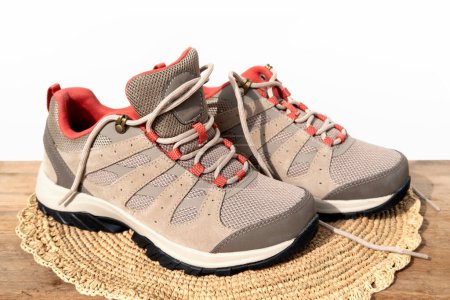Paar braun bequeme neue Trekking-Sneaker, beige wasserdichte Wanderschuhe mit Schnürung im Hintergrund, modernes Schuhwerk, Naturwildleder zum Wandern im Freien, Zelten