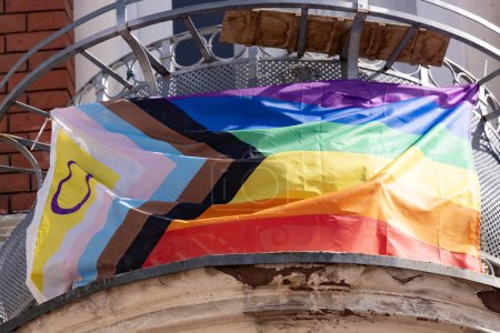 Regenbogenfahne Fortschritt auf Balkonhaus, mit schwarzen, braunen und blauen Linien trans Flagge in Chevron-Form. Erstellt von Daniel Quasar, internationale LGBT-Bewegung, Pride Month