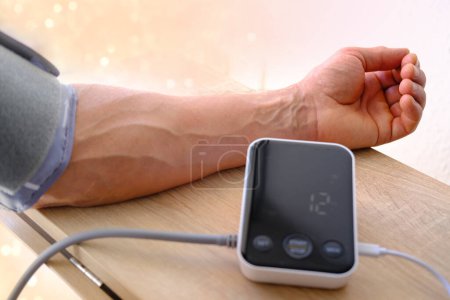 Photo for Measuring blood pressure, Senior man working with blood pressure machine at home to check his health, concept of health and heart - Royalty Free Image