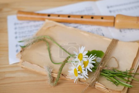 cozy scene with daisies flowers on rustic paper texture, wooden flute, sheet music, German traditions, dream imagination