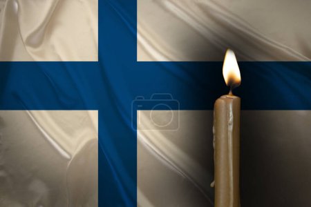 mourning candle burning front of flag Finland, memory of heroes served country, grief over loss, national unity in challenging times, state's history