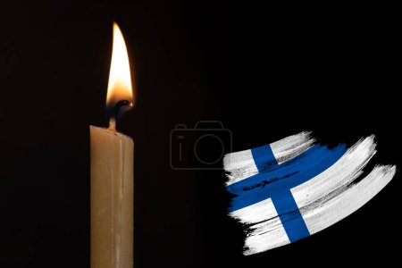 mourning candle burning front of flag Finland, memory of heroes served country, grief over loss, national unity in challenging times, state's history