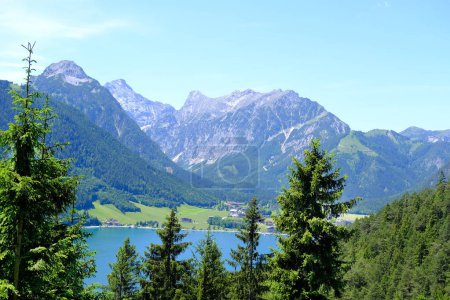picturesque Achensee lake in Austria, yachts and boats on water, green mountains rises above calm expanse of water, concept of beauty of nature, vacation by reservoir, water sports, resort place tyrol