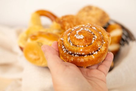 bun in female hand, Assorted blush-colored pastries, bread products, bakery, poppy seed rolls, balance between culinary delight and dietary awareness