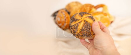 Assorted blush-colored pastries, bread products, bakery, buns, cheese and poppy seed rolls, pretzels and cottage cheese pies delights displayed in rustic woven basket panorama