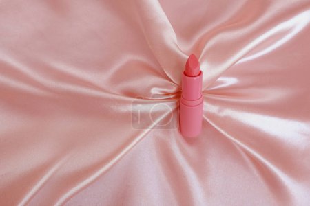 matte lipstick on a delicate pink background, pink silk fabric, close-up, the concept of decorative cosmetics, lip care, female beauty