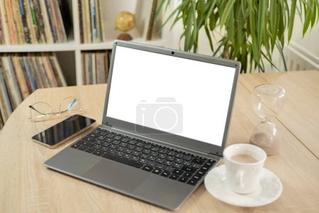 empty blank mockup, cup coffee, white laptop screen display for advertising, having virtual meeting, remote work, search online, home office, room interior with plant