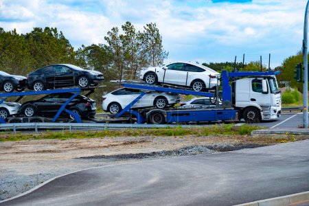 Photo for Car transporter carrier transports new Tesla vehicles from Gigafactory Berlin-Brandenburg manufacturing plant along highway, Logistics delivery services, Berlin - April 26, 2024 - Royalty Free Image
