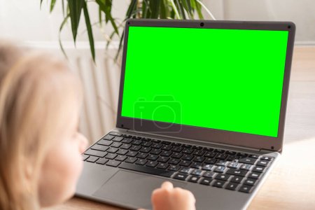 Photo for Preschool girl studying distance learning course, using computer for self-education and entertainment, monitor with green screen mockup, Parenting in digital age, cyber education, screen time - Royalty Free Image