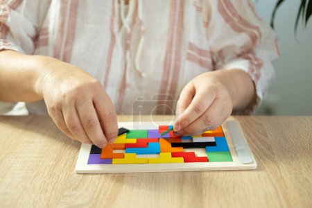 Mature female hands manipulate wooden geometric shapes intellectual puzzle, potential mental activity in preventing dementia and Alzheimer's disease, Keeping mind sharp