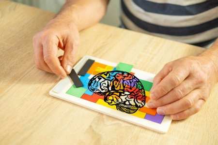Keeping mind active elderly male hand manipulates colorful wooden puzzle, brain health and mental well-being, cognitive training, elderly assistance