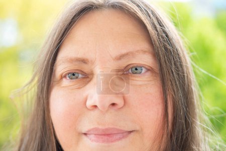 Mujer atractiva blanca positiva de 50 años mirando a la cámara, cara bonita retrato de cerca, arrugas en la piel, lifting facial, cambios en la piel relacionados con la edad, cosmetología inyección estética
