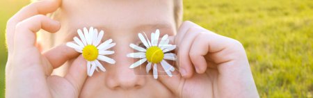 happy happy romantic boy 8 years old holding chamomile flower front of eyes, enjoy life, human happiness, tranquility nature, romantic connection between humans and natural world